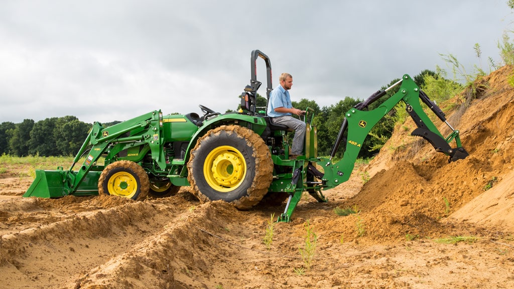 man on tractor with loader and backhoe and digging dirt with backhoe