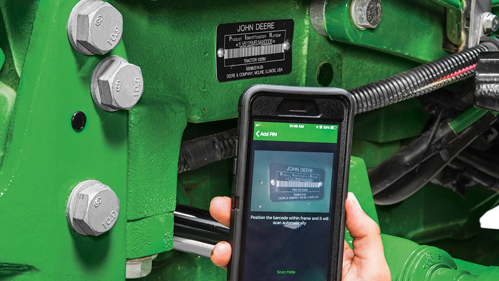 close up of mechanical parts of tractor with smart phone looking up information
