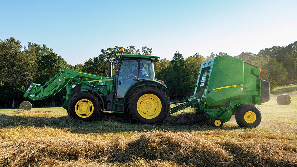tractor in field with round baler implement