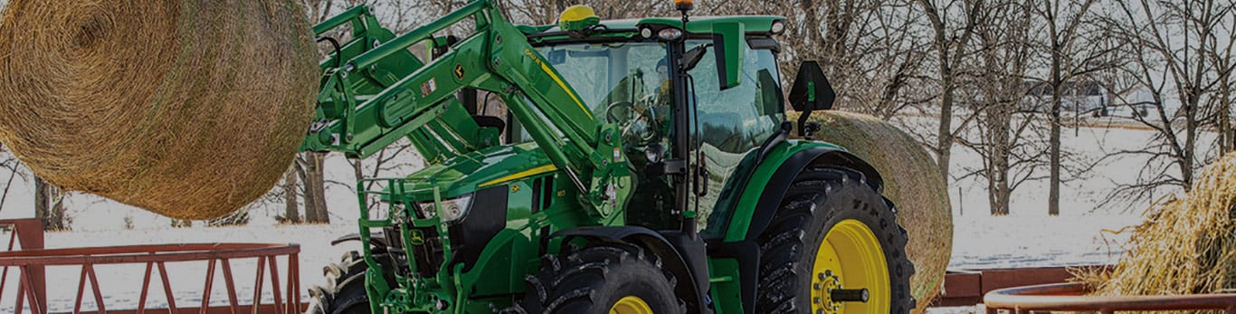 6R series tractor with front loaded hay bale in the snow