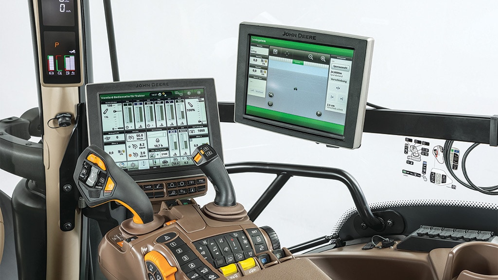 6r series tractor cab with multiple touchscreen monitors and joysticks