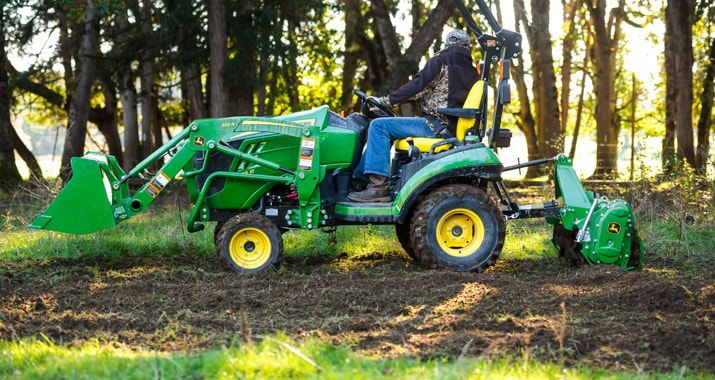 1025R Tractor tilling the ground with attached 120R Quick-Park loader and commercial quality tiller