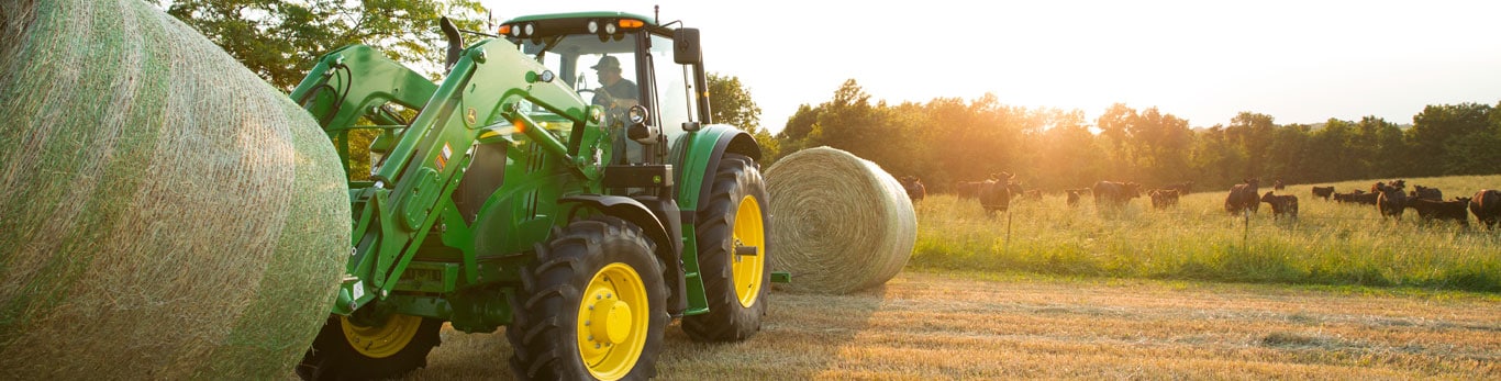 6 series utility tractor carrying hay near cattle