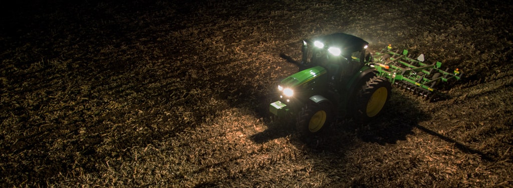 Image of row crop tractor in dark farm field with lights on