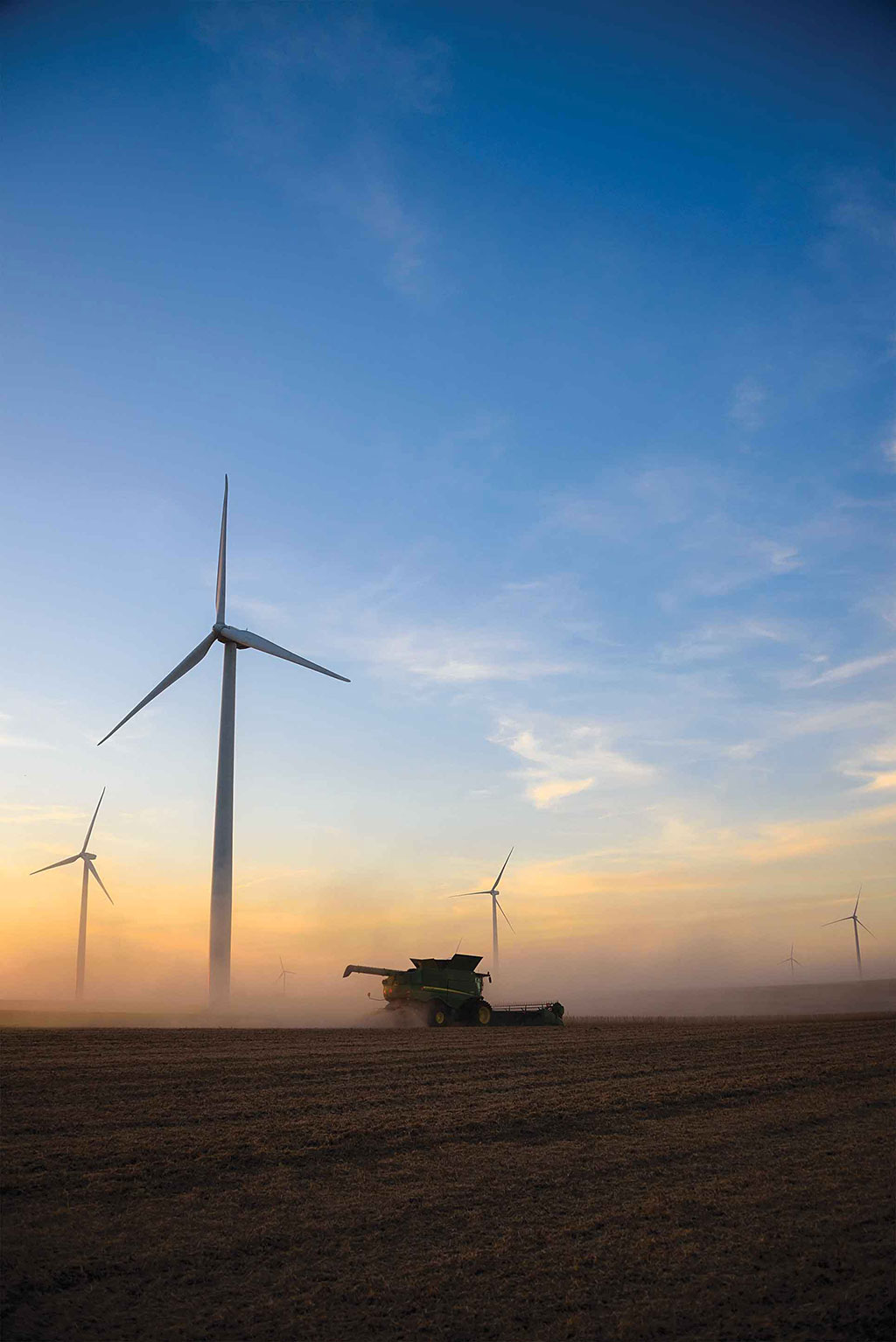 combine in field with wind turbines