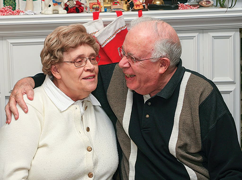 man hugging woman with one arm smiling