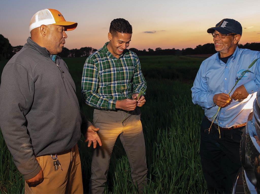 three farmers in the field smiling