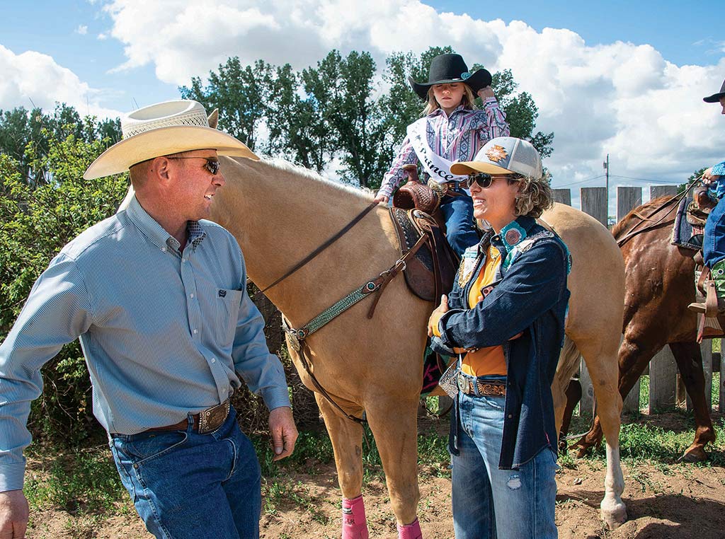 Two parents and a child on horseback talking