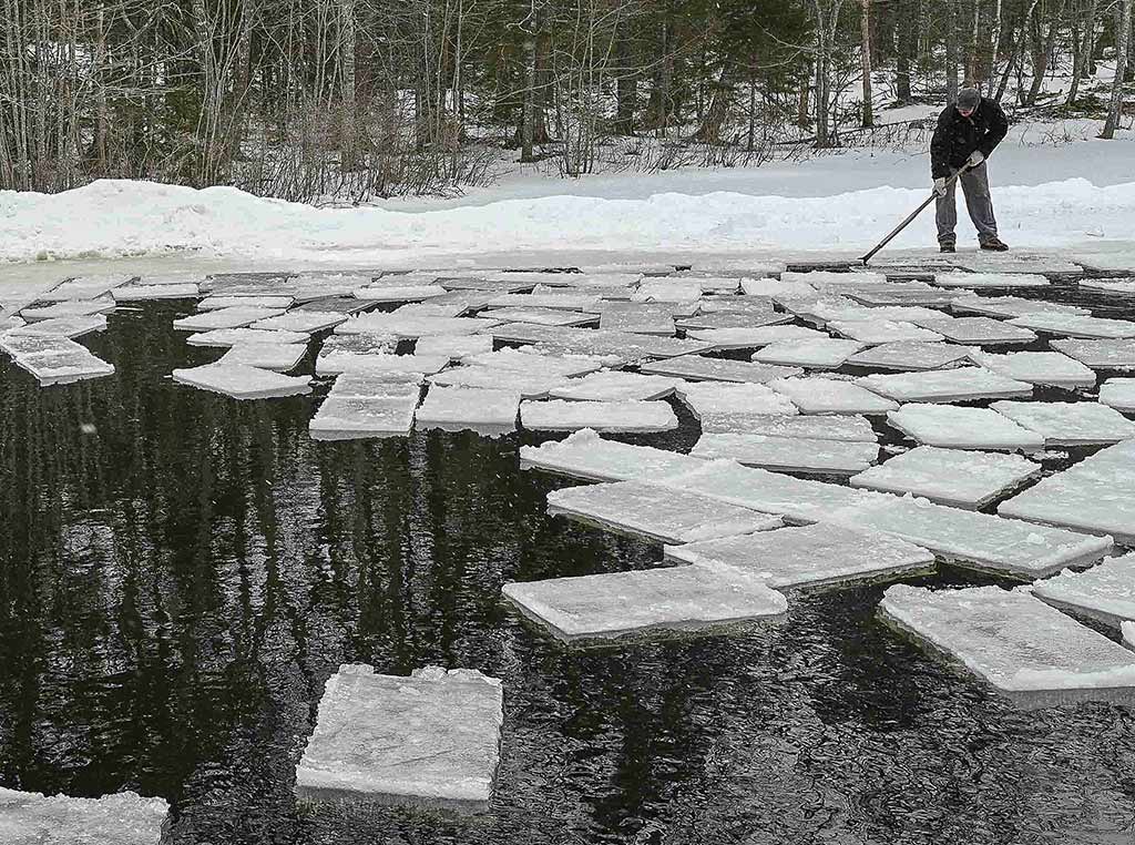 person nudging ice blocks in water with antique pike