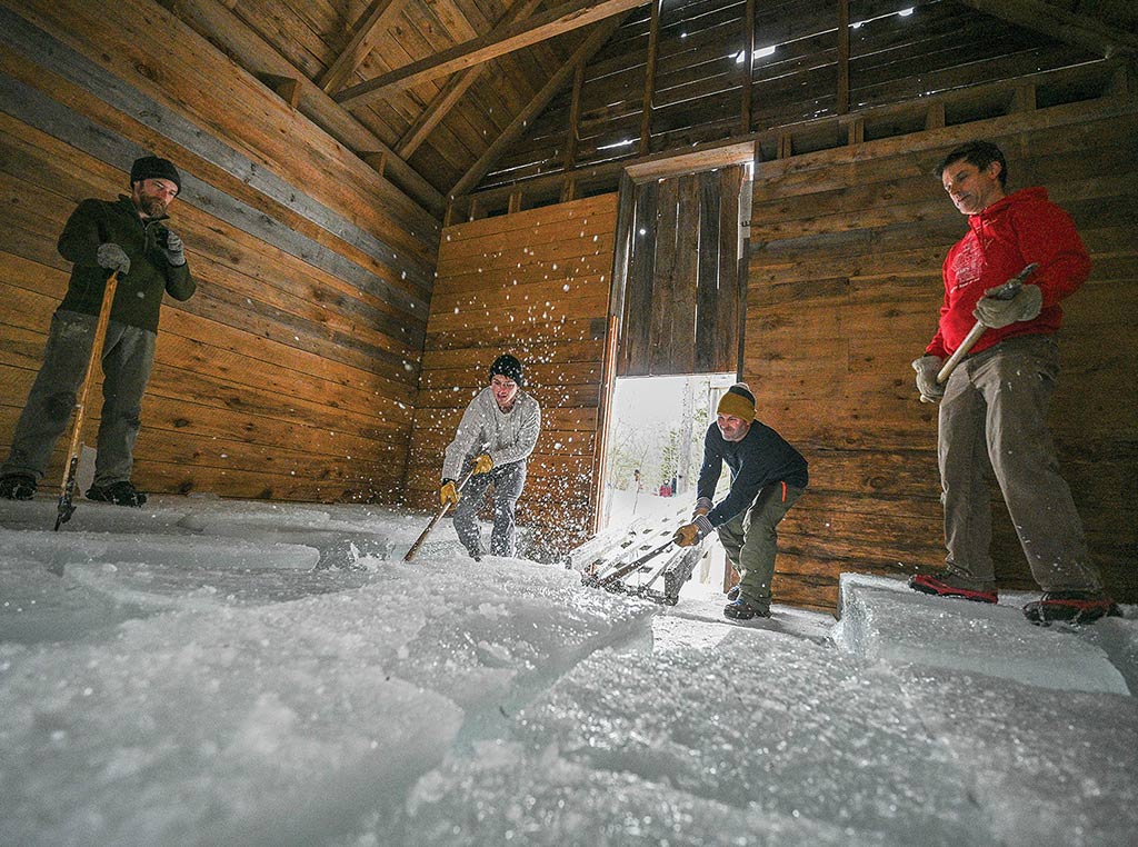 Ice sliding as four men work in the ice house