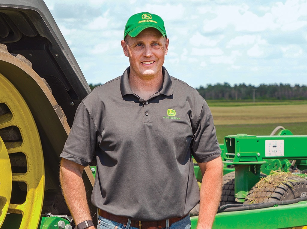 person smiling in front of Deere tractor