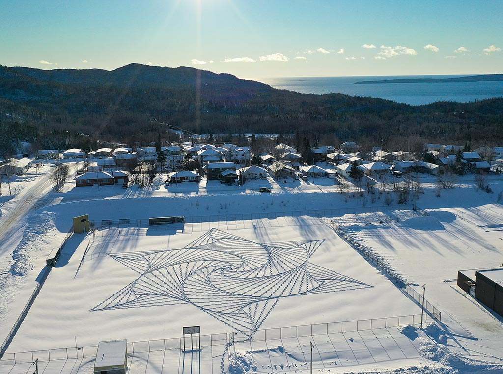 aerial view of swirling pattern in snow with mountains in distance