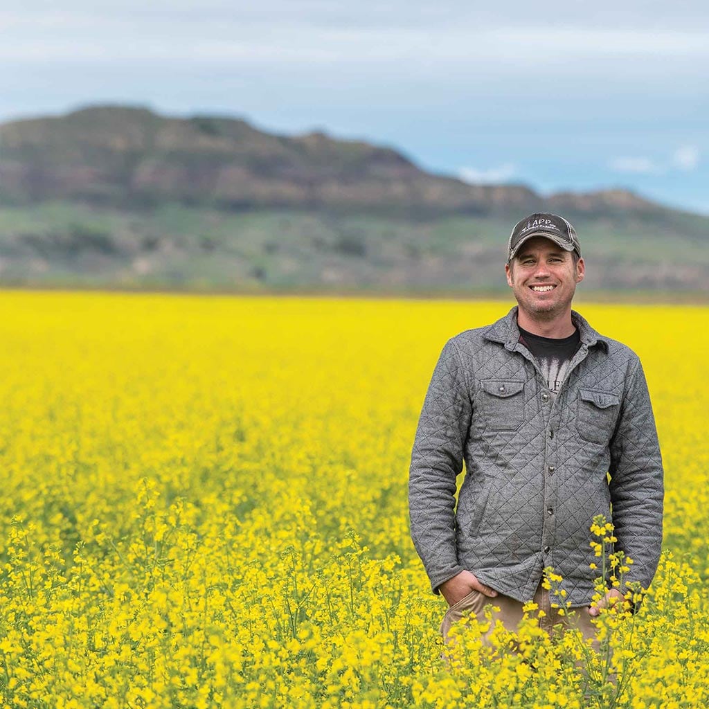 man standing in field of canola crops