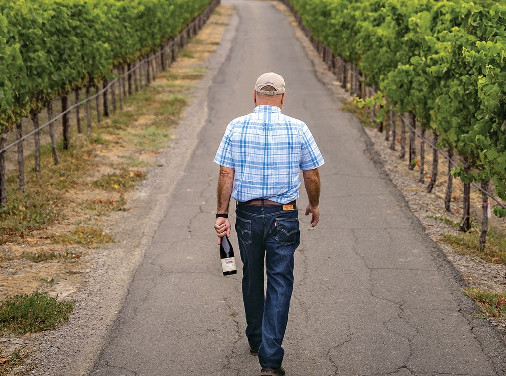 man walking on road holding wine bottle