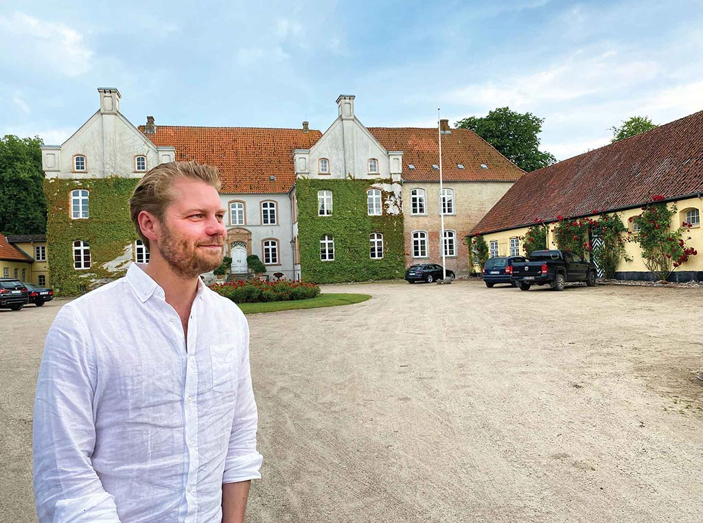 man standing in front of old estate building