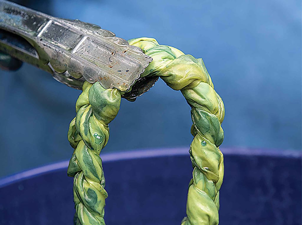 tongs pulling dyed cloth out of bucket