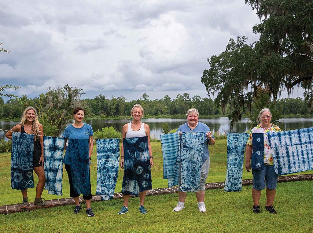 ladies standing on lawn presenting dyed cloth