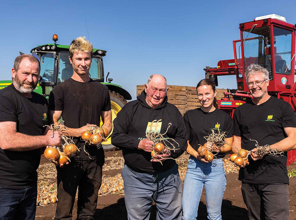 group of farmers holding onions in front of Deere tractor