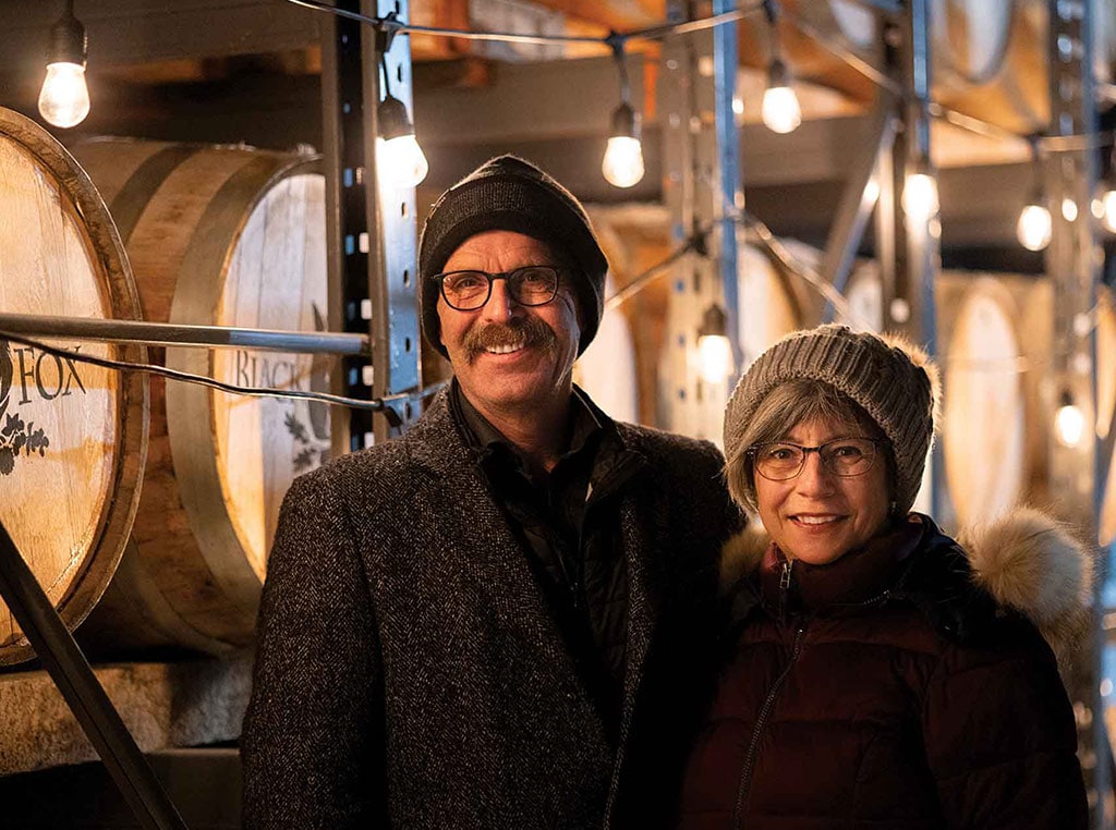 man and woman standing in front of row of barrels