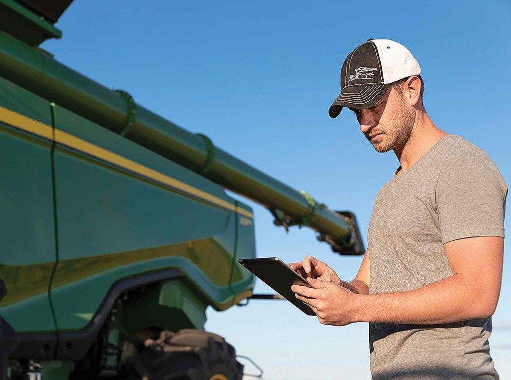 man using tablet next to Deere machinery