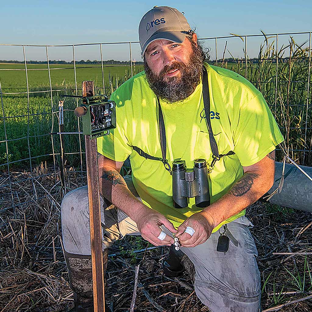 farmer kneeling over environmental conservation devices