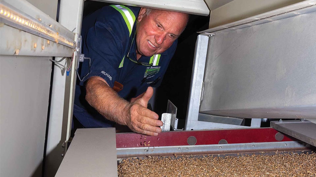 man reaching over grain