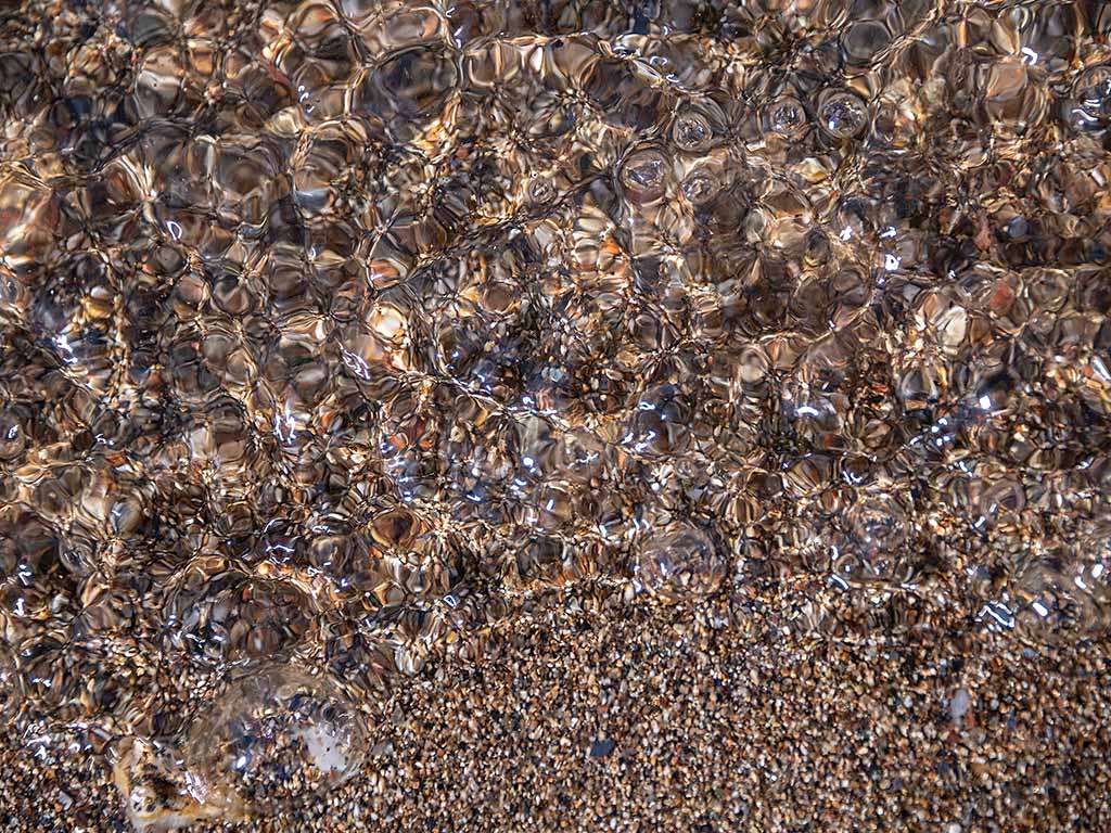 Closeup of pebbles in rippling water