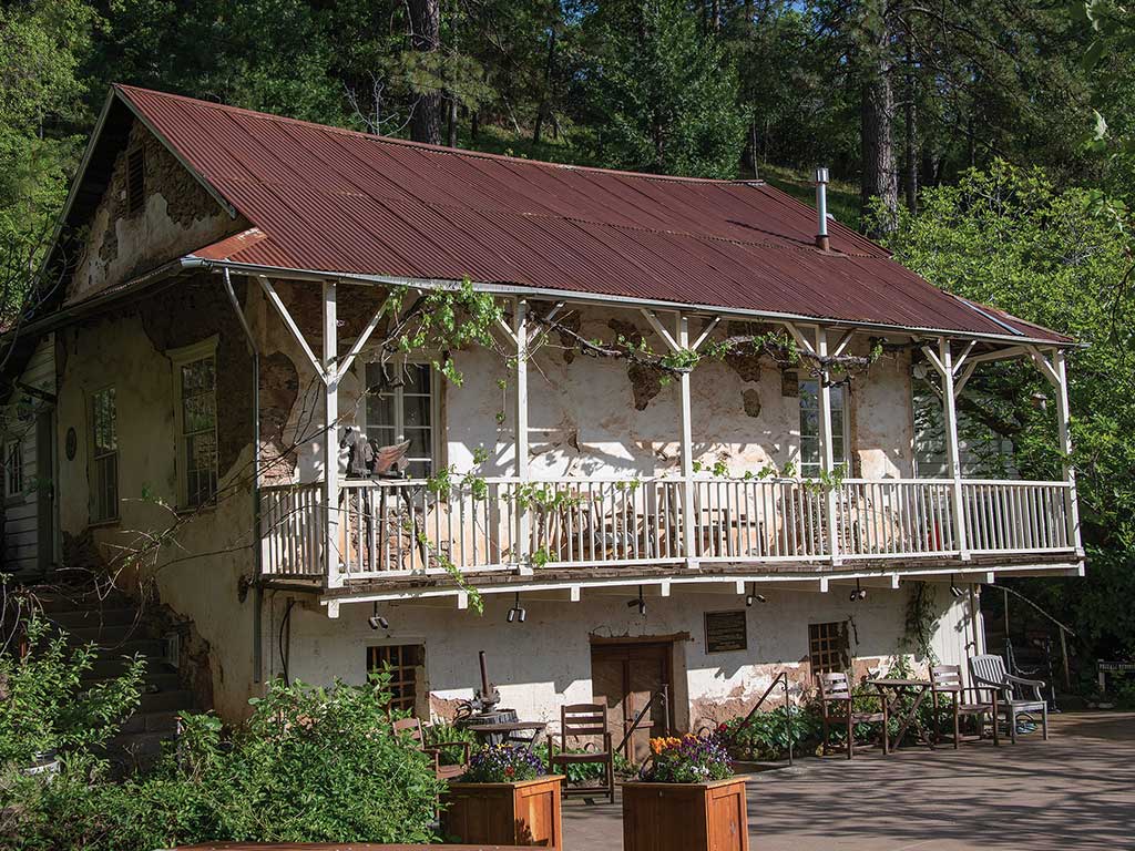  weathered house in front of trees on a hillside