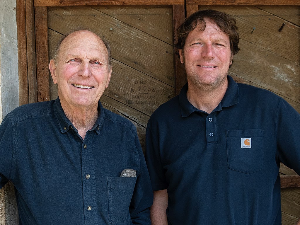  Two men smiling with blue collared shirts on