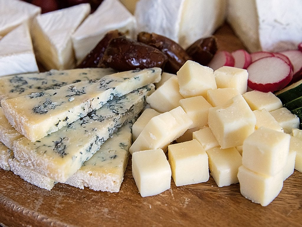  small piles of cheeses, nuts, and sliced radish