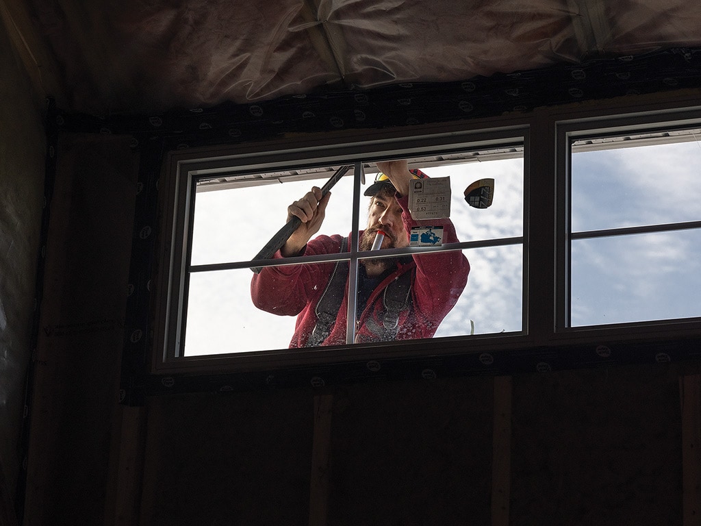  a worker hammering nails into a window frame