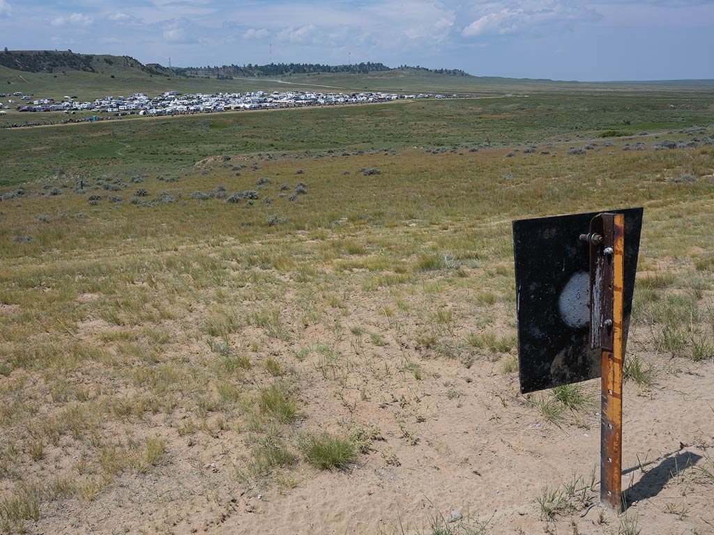 Metal target in open field with sprawling RV park in the distance