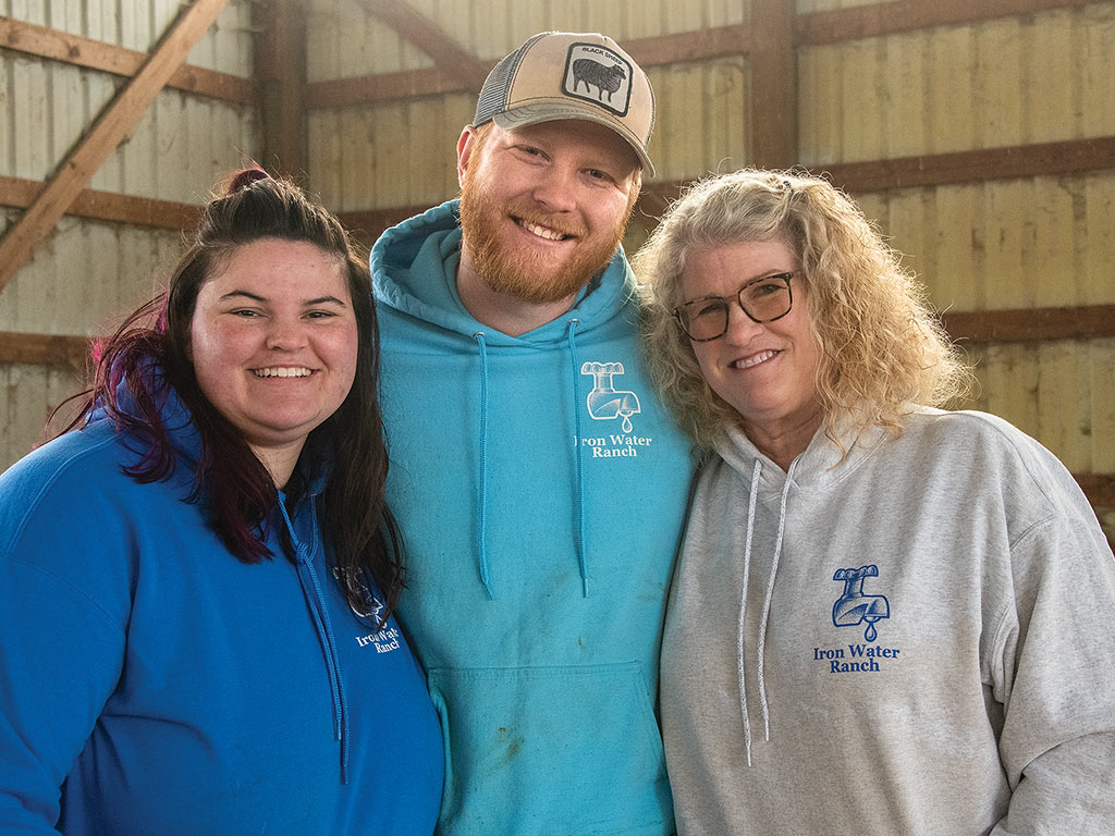 three people smiling in a barn