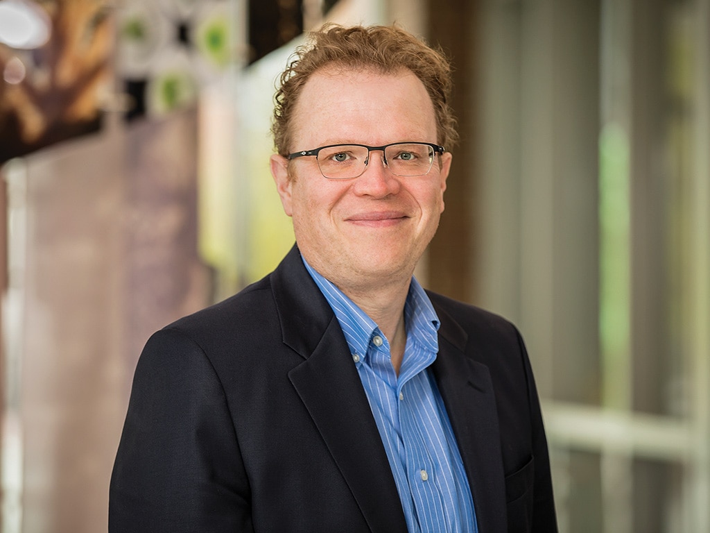 man with glasses and suit coat smiling