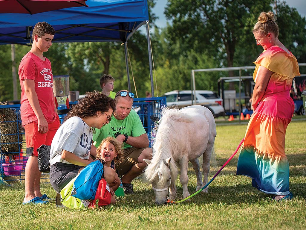  adults and children standing and squatting around a miniature pony