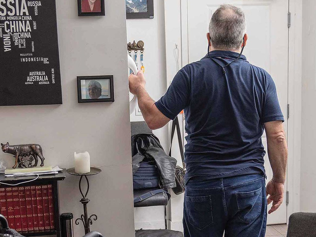 man facing door in home holding onto handle attached to wall