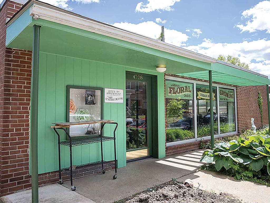 the outside storefront view of a green building with a metal stand out front