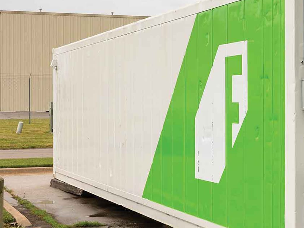Outdoor shot of a white container farm with a green and white logo on it
