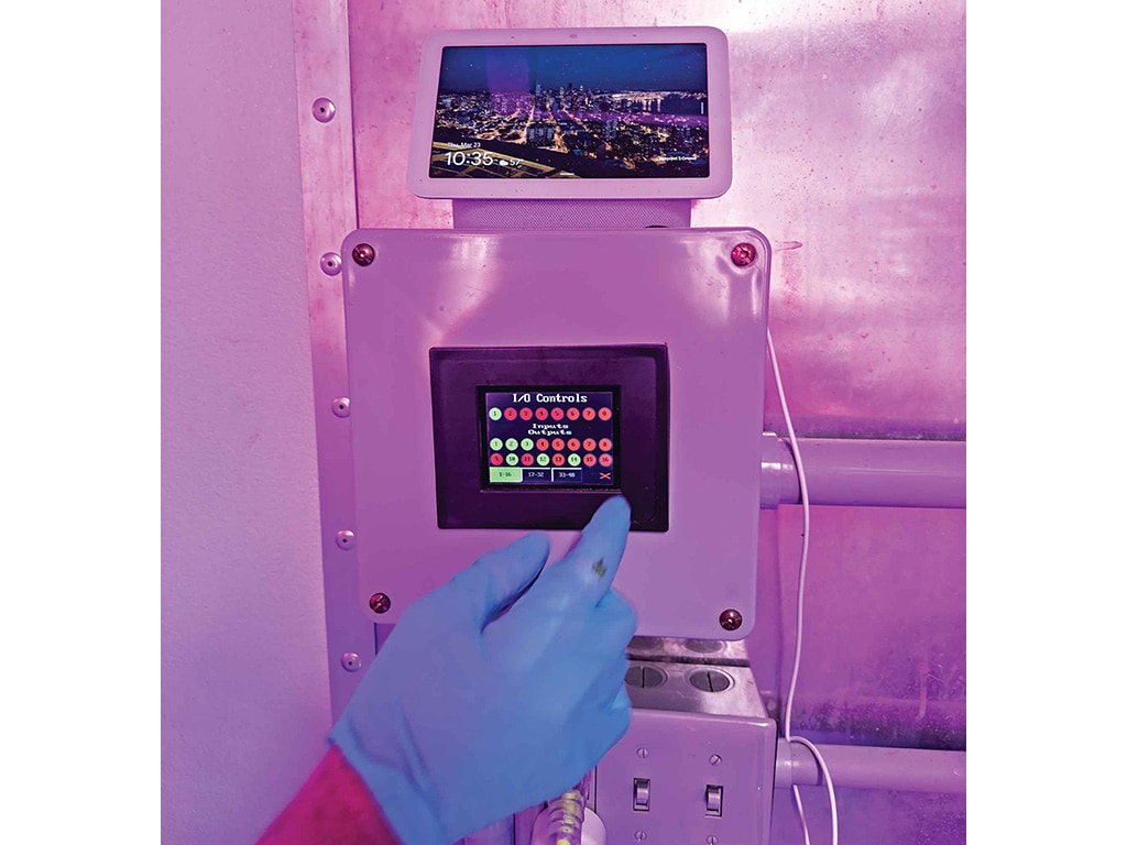 blue gloved hand operating climate controls inside a uv lit container
