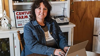 smiling woman at desk typing on tablet laptop