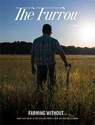 person standing in field with hand resting on shovel