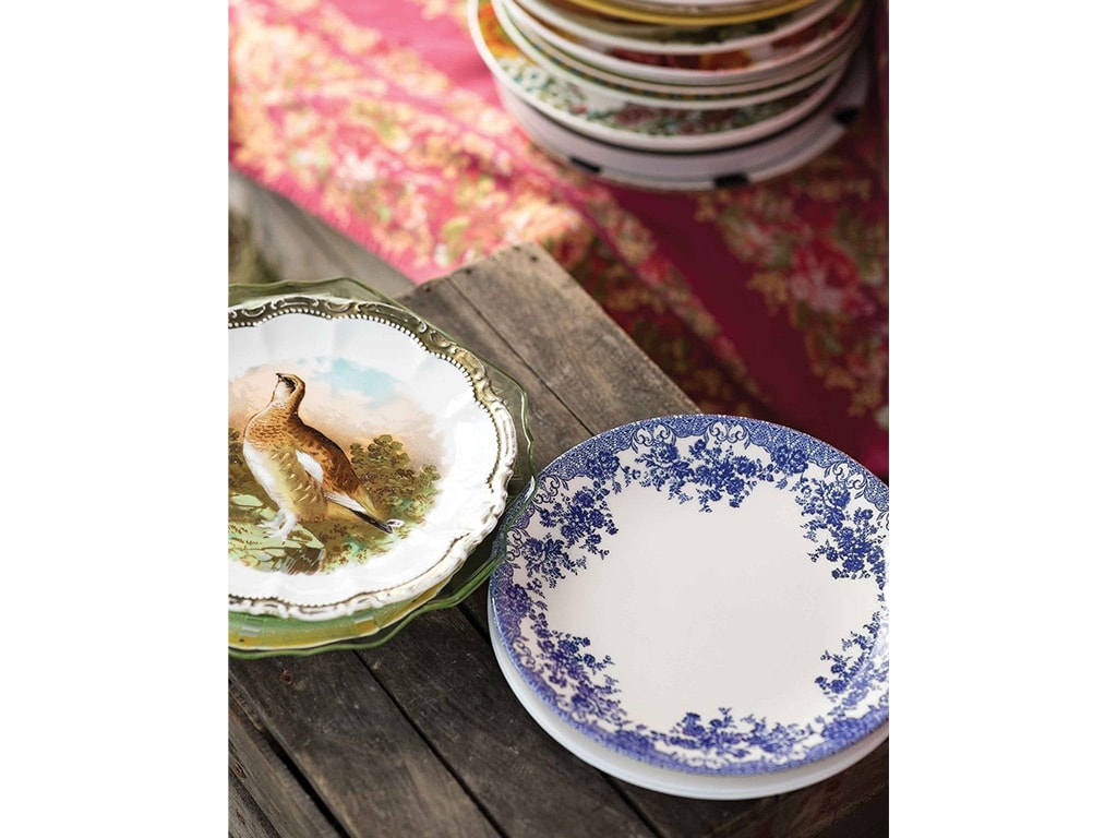 hodge podge of ornately detailed plates atop a wood table
