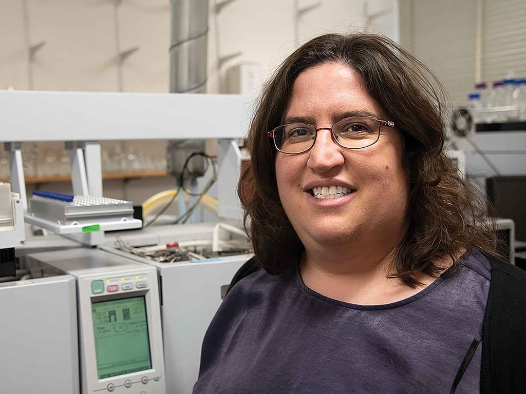 lab technician standing in a lab in front of a monitor