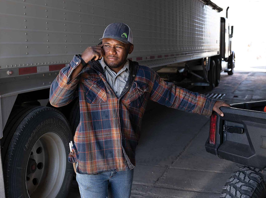 man on cellphone in barn next to semi truck