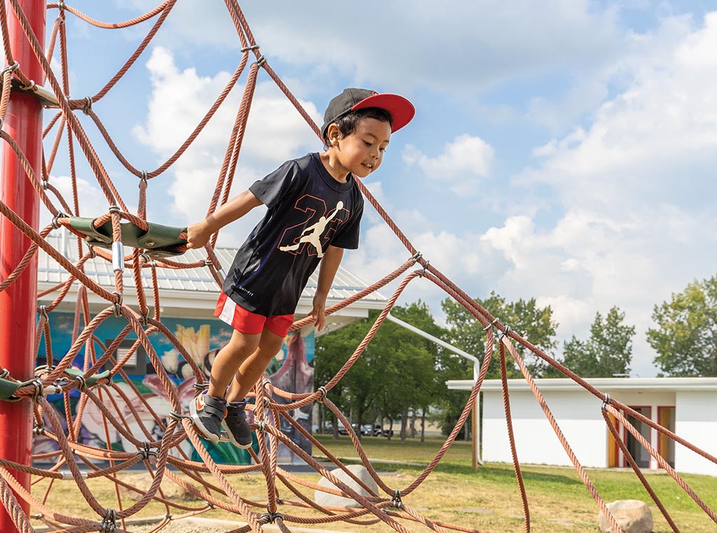 child hanging off of rope net