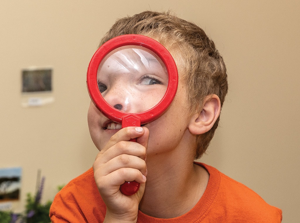 child looking through magnifying glass