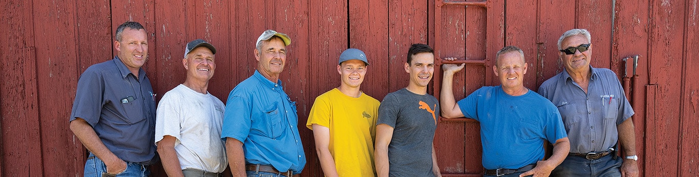seven men standing in front of a barn door