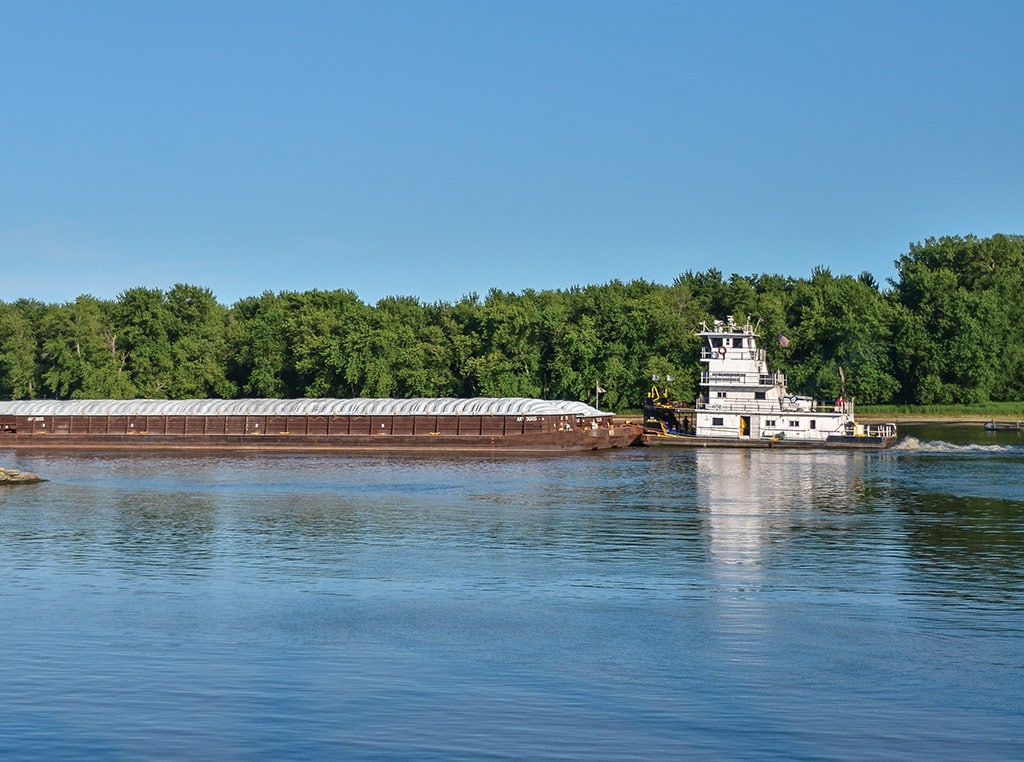 tugboat on a river pulling long freight barge