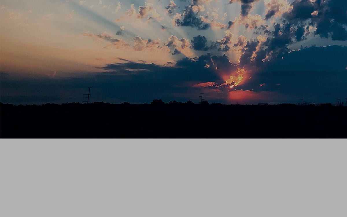 sunset gleaming through clouds over farmland