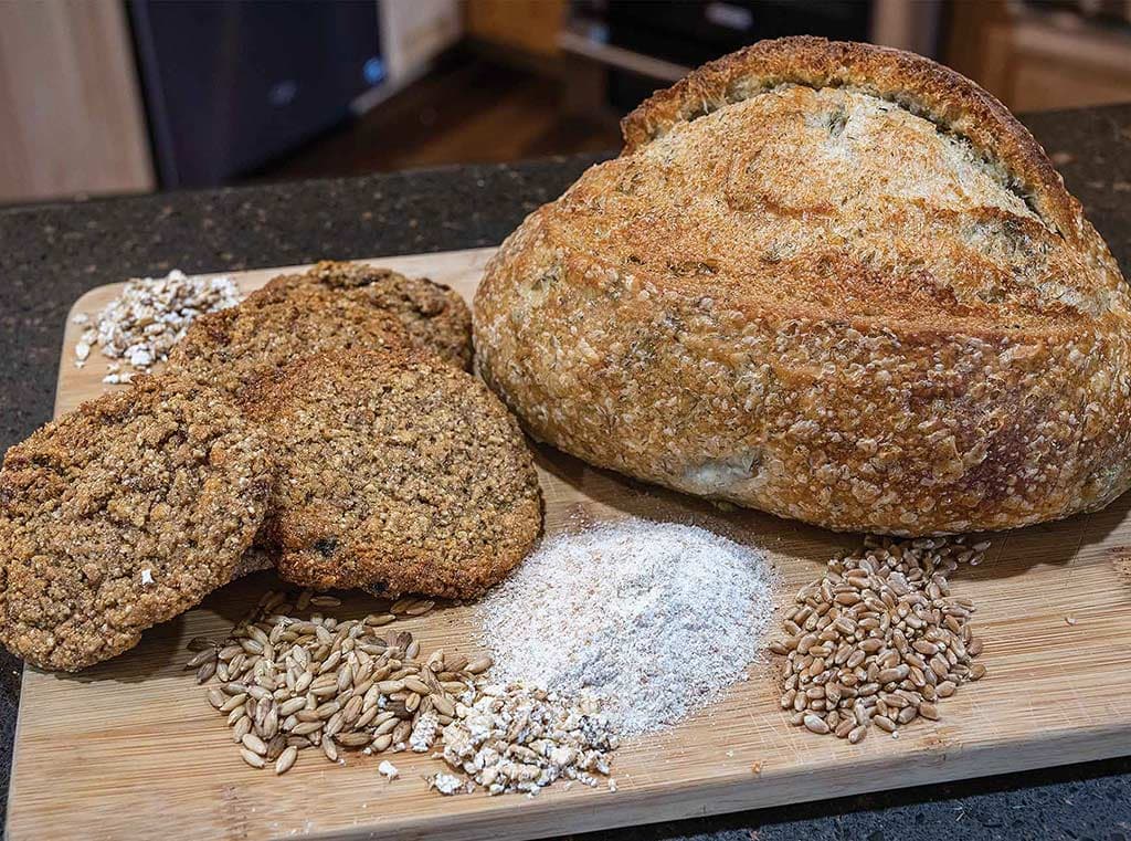 round loaf of bread with cookies and small piles of grains and flour